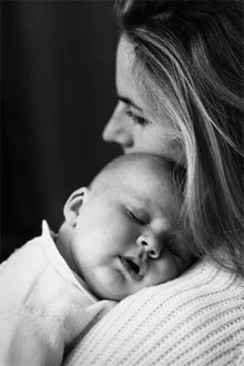Madre durmiendo a su bebe en brazos