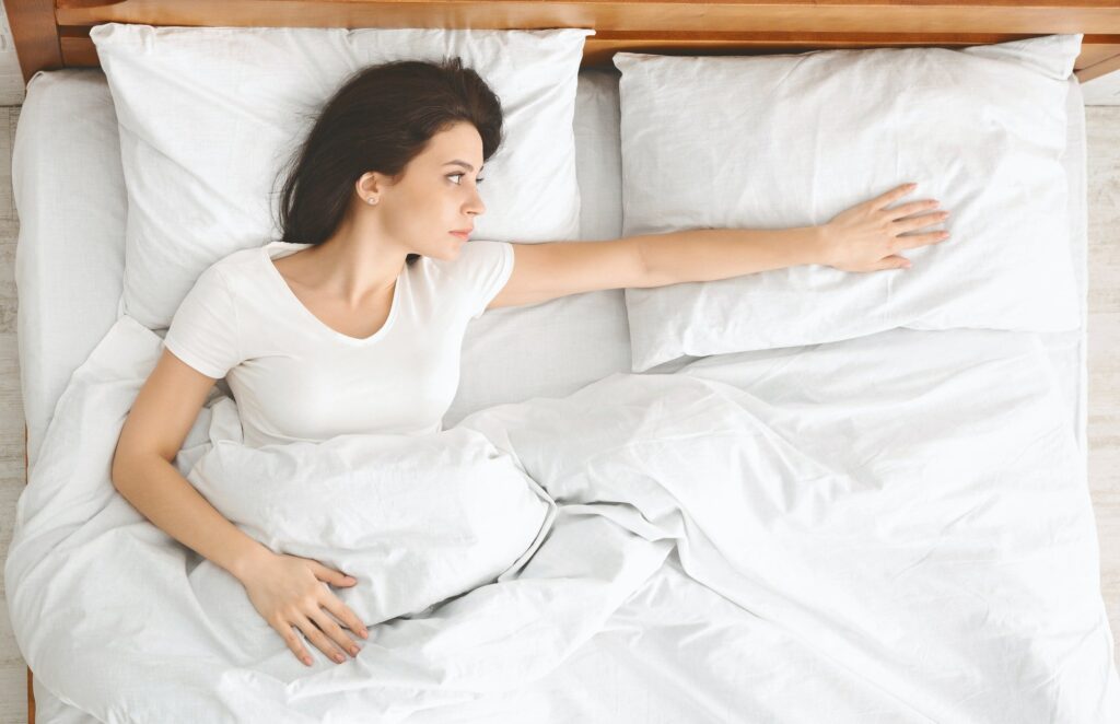 Depressed young woman lying in bed and feeling upset